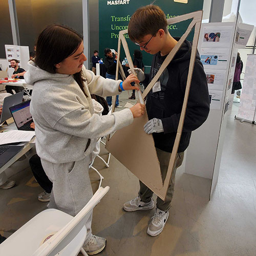 Two students assembling a triangular cardboard prototype